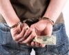 A man handcuffed while holding money