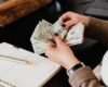 Woman counting money at modern office table